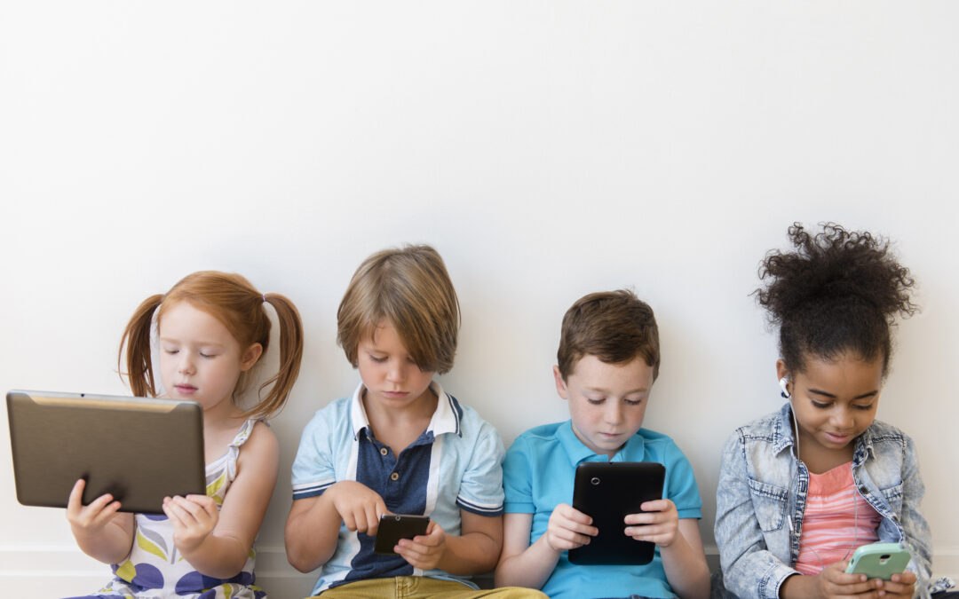 Four children sitting on bench and using tablets and phones, representing managing a healthy relationship with technology