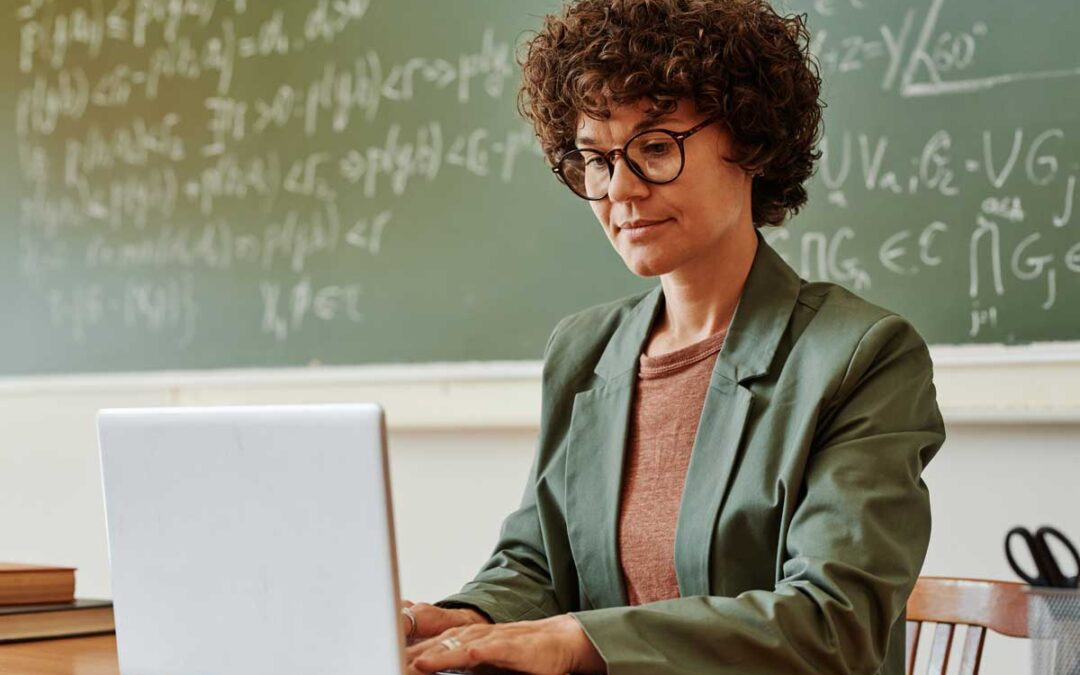 a female teacher sitting at her computer researching the best ai for teachers