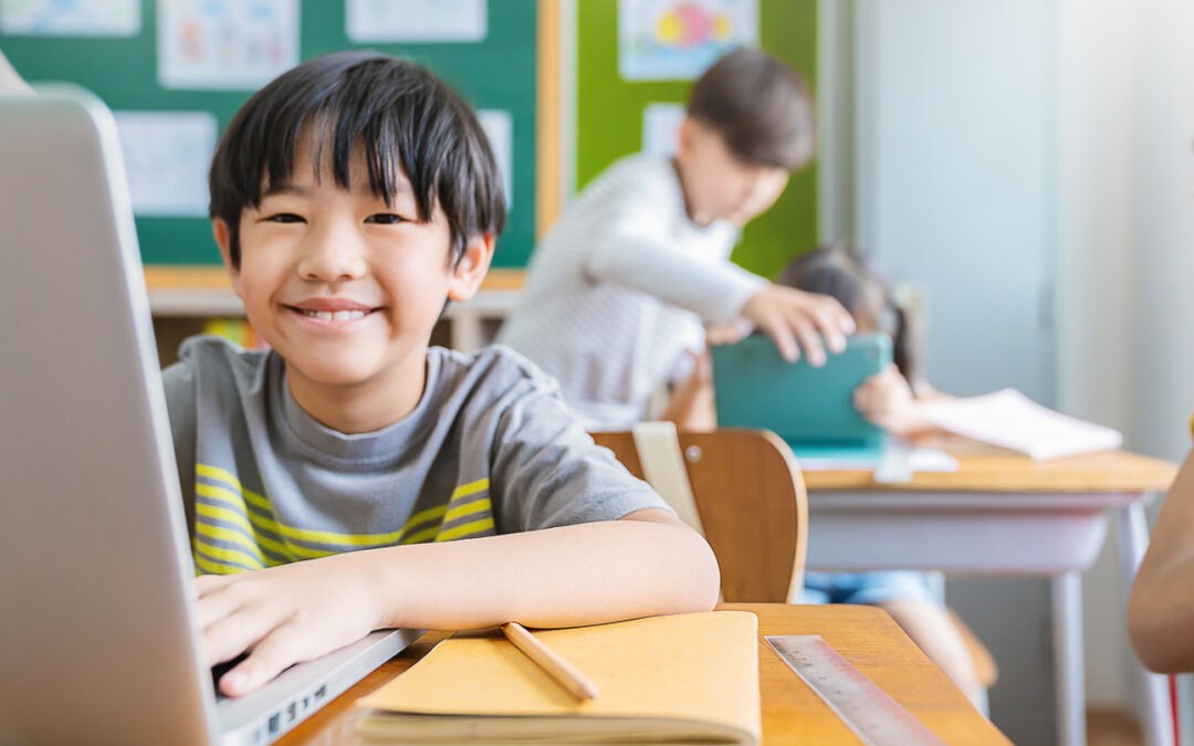 Young boy using computer in school while receiving digital literacy education