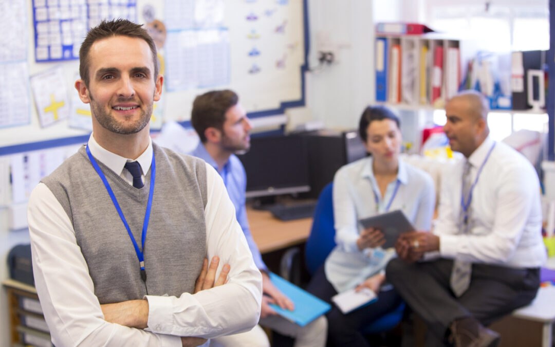 Small group of teachers meeting in classroom to discuss new technology implementation